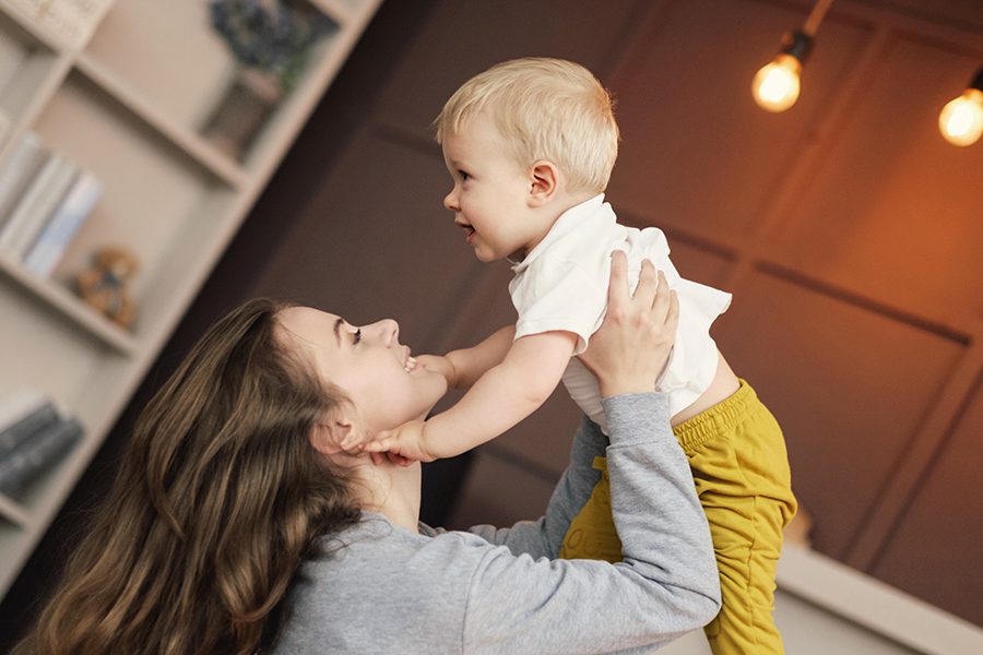 Personal Insurance - Angled View of Mother Holding Child and Smiling in the Family Living Room